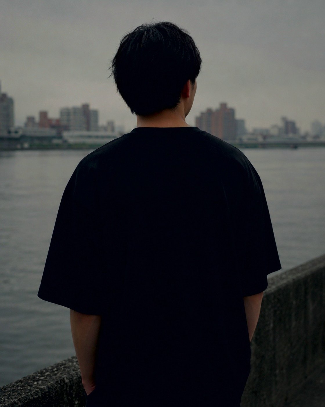 川沿いに立つ、S/S TEEの後ろ姿